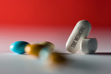 The medicine,  inscription on pill, scattered tablets on red background, concept