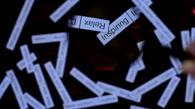 Hand with magnifier focuses on phrase Creative. Finding solutions. Tag cloud on  dark wooden table.