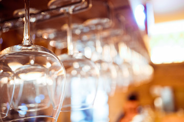 Glasses of wine. Glasses hanging above the bar in the restaurant. Empty glasses for wine. Wine and martini glasses in shelf above a bar rack in restaurant. blue lights, blue background, night life