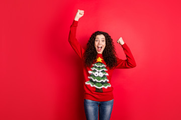 Wow unbelievable newyear party. Portrait of crazy funny funky girl raise fists scream yeah celebrate x-mas wear traditional seasonal clothes with christmas tree decor isolated red color background