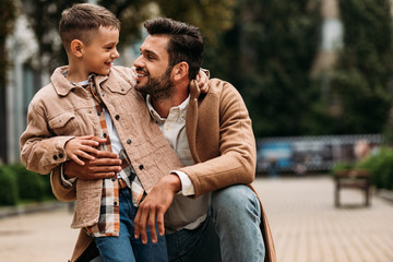 Happy father and son embracing and looking at each other on street