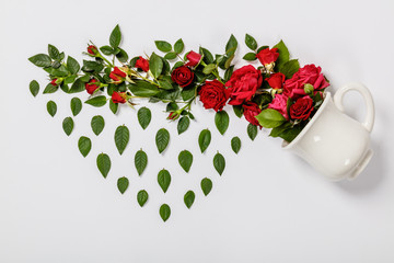 Creative layout made of coffee or tea cup with red roses on white background