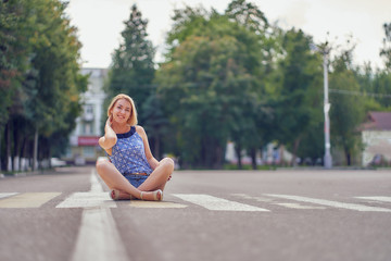 woman sits on a road at a pedestrian crossing. crosswalk