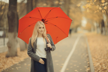 autumn look, sunny day a young girl with an umbrella walks in a yellow park in October