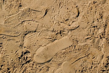 Traces of people’s shoes on a sandy surface. Top view of shoes prints on the sandy beach