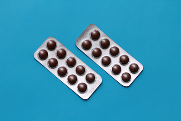 Set of pills blisters isolated on solid blue background. Medical concept. Potent drugs. Brown pills.  Your text space. 
