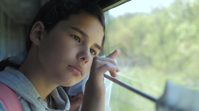 sad girl lifestyle looks out the train window. travel transportation railroad concept. teen girl misses traveling in a train compartment looking out the window. long train journey by rail