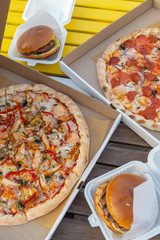 Unhealthy snacks delivery in boxes: italian margherita and chicken pizza, beef burgers with cheddar...