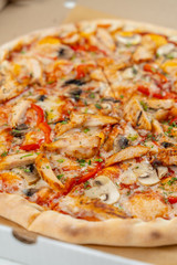 Hot chicken pizza with mushrooms and bell pepper with a thick crust in a delivery box