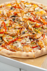 Hot chicken pizza with mushrooms and bell pepper with a thick crust in a delivery box