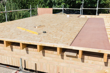Renovation projects. Building of extension of the existing house, unfinished wooden roof structure, brick walls, view from scaffoliding, selective focus © Liliya Trott