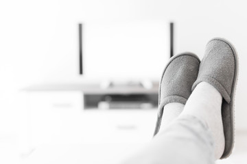 Man looking at TV with legs on the table in living room.
