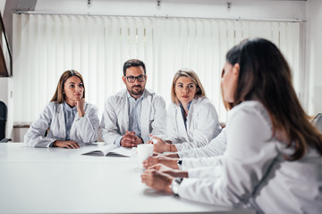 Serious medical team talking while sitting at the table.