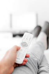 Man looking at TV with legs on the table in living room.