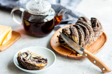  Poppy seed roll with butter and tea. Baking with poppy seeds. The work of the baker. Baking rolls with poppy seeds and pies in the kitchen. Bakery, cook together.