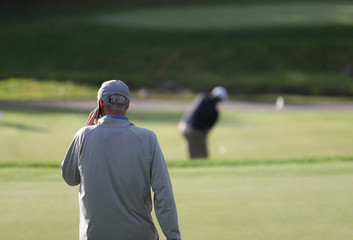 a golfer uses a cell phone on a practice green