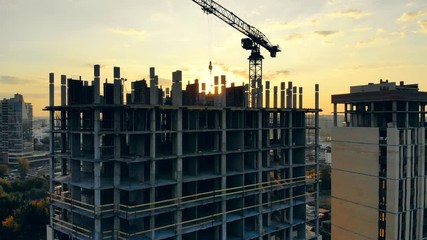 City sunset and a multistory house under construction. Aerial view of construction site.