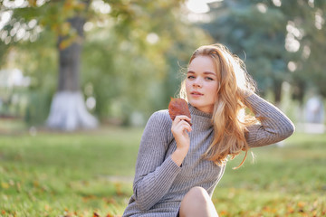 woman in the park. sitting on fallen leaves. closeup