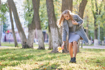 woman in the park in golden autumn. collects fallen leaves
