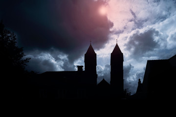 Silhouette of medieval castle and the cathedral church, night over dark sky background with the full moon