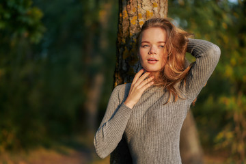 red-haired young woman in a park in golden autumn. posing in a gray dress. close-up