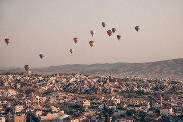 Landscape with a lot of hot air balloons in the sky over the city. Famous Turkish region Cappadocia with mountains and cave cities. View from below.