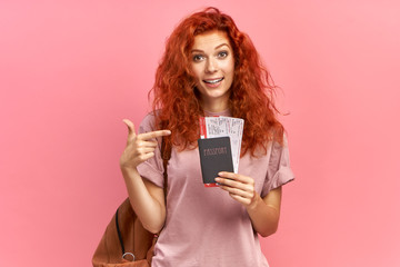 Excited traveller ready for trip, showing passport and plane tickets, rejoices having tour abroad with boyfriend, has special offer from travel company, isolated over pink background