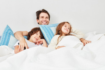 Vater und Kinder im Bett schauen Fernsehen
