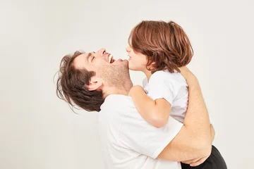 Fotobehang Glücklicher Vater umarmt lachend seinen Sohn © Robert Kneschke