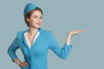 Beautiful stewardess holding blank on her hand. Blue background. - 292878016