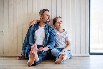 Mature father with small son sitting indoors, talking.