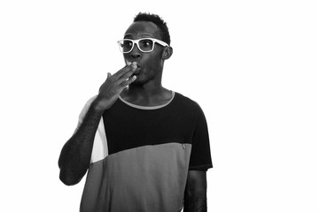 Young black African man looking shocked while covering mouth