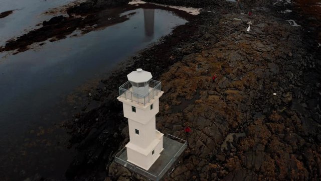 Aerial tilt up view of a lighthouse on the fishing village of Akranes in West Iceland