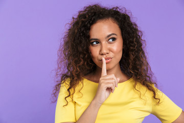 Fototapeta premium Portrait of afro american thinking woman showing silence gesture