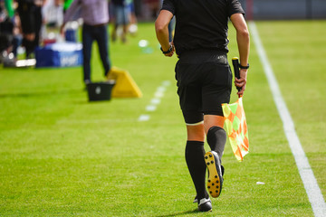 Sideline referee runs during soccer match.