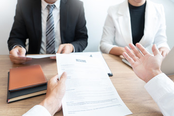Serious man has a business meeting reading a resume about hiring decision during a job interview in company, attractive and professionally dressed, employment recruitment concept.