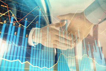 Double exposure of financial graph on cityscape background with two businessman handshake. Concept of stock market deal