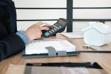 businessman calculating budget with calculator. saving money for buying house property. real estate investment