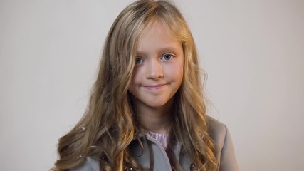 Attractive portrait of cute smiling teen girl with blonde hair posing on camera on the background of white wall - Powered by Adobe