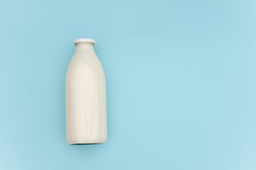 Milk in glass bottle on blue background with copy space. Flat lay Top view
