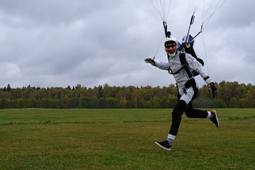Skydiving. A skydiver has just landed on the field.