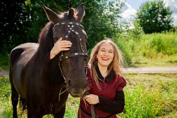 Fototapeta premium Beautiful caucasian young girl walking with a horse and enjoys summertime in countryside.