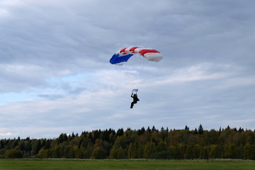 A skydiver is landing on the field.