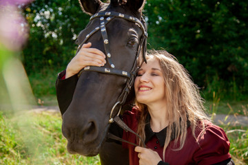 Obraz premium Beautiful caucasian young girl walking with a horse and enjoys summertime in countryside.