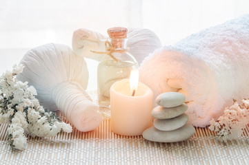 Obraz na płótnie Canvas Spa treatments set with herbal compressing ball, oil bottle, candles and towel on bamboo plate background