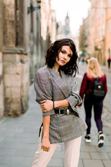 Young pretty girl in fashionable clothes walk on the street of old city center, sunny day weather,...
