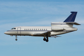fotografía perfecta de un avión jet privado de perfil, tiene las ruedas desplegadas y a punto de aterrizar