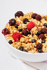 White bowl of muesli with berries, against white background, with negative space available.