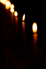 Glowing Candles For Religious Tradition. Beautiful candles burning in a row, line pattern at a temple or church during Diwali celebration, ceremony at night. Background stock photo of festive season.