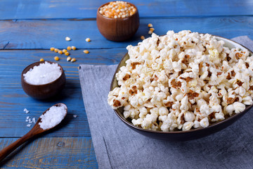 Popcorn, unpopped kernels and sea salt on blue wooden table